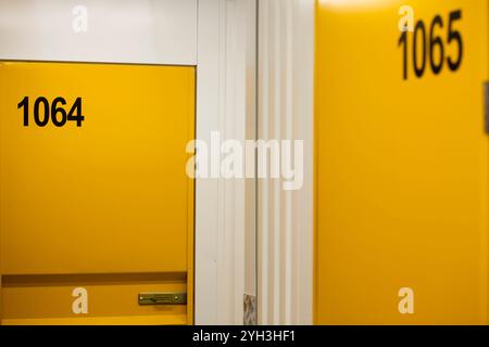 Primo piano di due sportelli gialli dell'unità di conservazione numerati 1064 e 1065 in un'unità di stoccaggio autonoma. Foto Stock