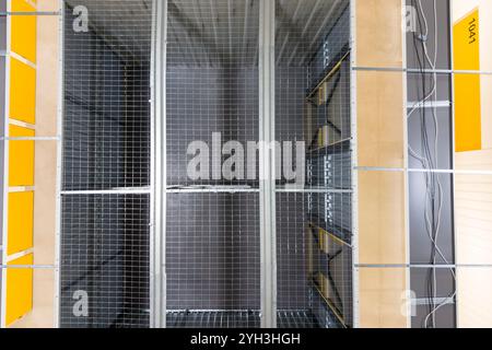 Vista dall'alto delle unità di stoccaggio in metallo organizzate con pareti a griglia e marcatori gialli in una struttura. Foto Stock