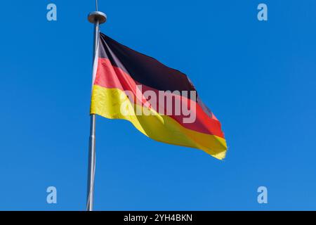 Vista della bandiera nazionale della Germania contro un cielo blu Foto Stock