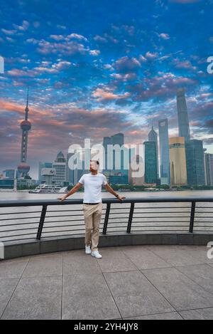 Vista dello skyline di Shanghai dal Bund, con la Oriental Pearl Tower e la Shanghai Tower. Una persona si trova sulla passeggiata lungo il fiume Huangpu Foto Stock