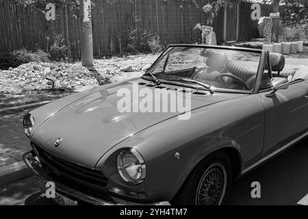 Mitzpe Ramon, Israele - 10 maggio 2024: Fiat 124 Sport Spider auto da collezione d'antiquariato decappottabile parcheggiata sulla strada laterale in bianco e nero Foto Stock