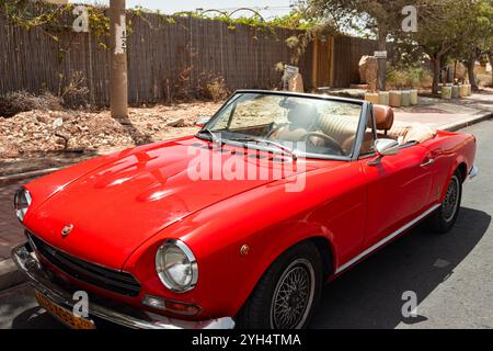 Mitzpe Ramon, Israele - 10 maggio 2024: Fiat 124 Sport Spider rosso collezionista d'epoca cabriolet parcheggiata sulla strada laterale Foto Stock