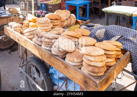 Pane tradizionale appena sfornato (Khobz) su un carrello in vendita al mattino in un tipico mercato di strada del Marocco. Foto Stock