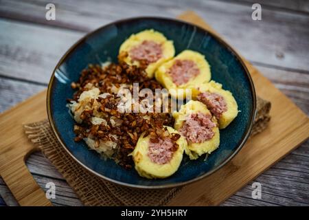 La scena presenta un tradizionale piatto ceco composto da gnocchi di patate ripieni di carne affumicata. I ravioli sono accompagnati da crauti fermentati Foto Stock