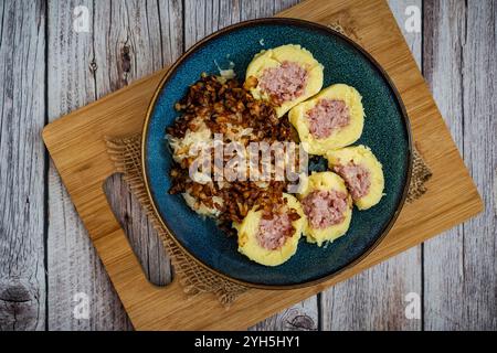 La scena presenta un tradizionale piatto ceco composto da gnocchi di patate ripieni di carne affumicata. I ravioli sono accompagnati da crauti fermentati Foto Stock