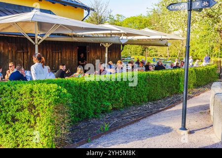 Area con posti a sedere all'aperto presso il ristorante con persone che si godono la giornata di sole sotto grandi ombrelloni. Foto Stock