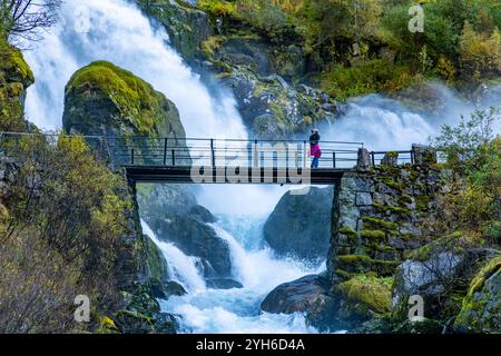 Woman scatta una foto della famosa cascata Kleivafossen nel Jostedalsbreen National Park, formata dalla fusione glaciale della briksdalbreen Foto Stock