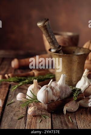 Bulbi d'aglio con rosmarino su un vecchio tavolo di legno. Copia spazio. Foto Stock