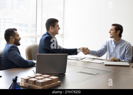 Squadra di allegri uomini d'affari che stringono la mano dopo la negoziazione Foto Stock