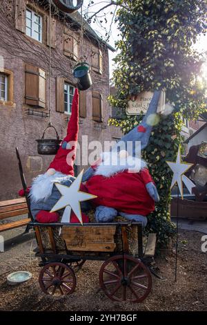 EN la esquina de una plaza, unos gnomos en una carretilla como decoración navideña. Eguisheim, Alsacia, Francia Foto Stock