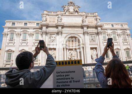 Roma, Italia. 9 novembre 2024. I turisti scattano foto alla Fontana di Trevi durante i lavori di ristrutturazione. Restauro della Fontana di Trevi: Oggi è stato inaugurato un passaggio sospeso temporaneo per consentire ai visitatori di vedere la fontana più vicina durante i lavori di ristrutturazione, il 9 novembre 2024. I lavori comprendono la pulizia delle pietre nella parte inferiore del monumento e dei giunti di cementazione, che dovrebbero essere completati entro la fine dell'anno. Gruppi limitati di visitatori potranno attraversare la fontana su un passaggio sopraelevato durante la manutenzione. Credito: SOPA Images Limited/Alamy Live News Foto Stock