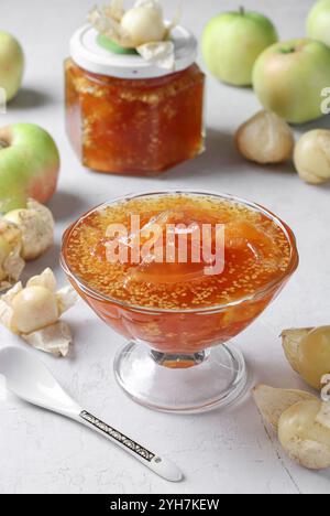 Marmellata fatta in casa physalis trasparente e mele in ciotola e vaso di vetro su sfondo grigio Foto Stock