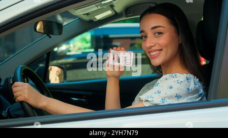 Felice felice positivo caucasico sorridente donna donna donna autista proprietario di auto acquirente cliente seduto all'interno dell'automobile guardando la fotocamera che mostra il digitale Foto Stock