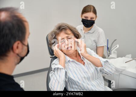 Il paziente ad un appuntamento con i dentisti si lamenta con uno specialista per il dolore Foto Stock