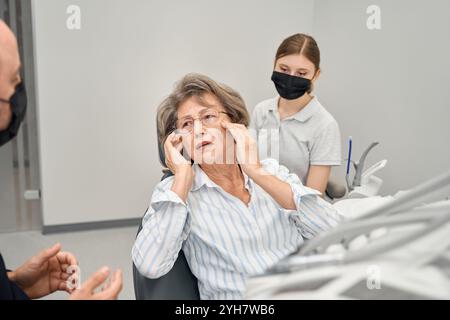 Il pensionato si lamenta con uno specialista per il dolore all'appuntamento con i dentisti Foto Stock