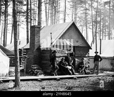 Ufficiali di fronte ai quartieri invernali al quartier generale dell'Armata del Potomac, Brandy Station, Virginia. Fotografia dal principale teatro orientale della guerra, dicembre 1863-aprile 1864. Creato nel mese di febbraio 1864. Situata sulla Orange and Alexandria Railroad, Brandy Station servì come deposito di rifornimenti e passeggeri dell'Union Army of the Potomac durante il loro accampamento invernale del 1863-1864 in quest'area. Qui a Brandy Station, tra il trambusto di carico e scarico di rifornimenti e personale, i soldati potrebbero farsi fotografare per 1,50 dollari o spendere i loro soldi per qualsiasi altro oggetto Foto Stock