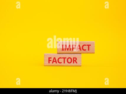 Simbolo del fattore di impatto. Blocchi di legno con parole Impact Factor. Bellissimo sfondo giallo. Concetto di business e fattore di impatto. Copia spazio. Foto Stock