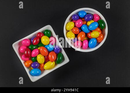 Palle di gomma da masticare di diversi colori in contenitori lucidi in terracotta con uno sfondo colorato omogeneo per il posizionamento del testo Foto Stock