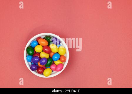 Palle di gomma da masticare di diversi colori in contenitori lucidi in terracotta con uno sfondo colorato omogeneo per il posizionamento del testo Foto Stock