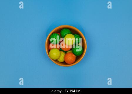 Palle di gomma da masticare di diversi colori in contenitori lucidi in terracotta con uno sfondo colorato omogeneo per il posizionamento del testo Foto Stock