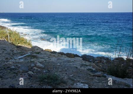 Onde dolci si infrangono contro la costa frastagliata, evidenziando la bellezza serena del mare sotto il sole. Foto Stock