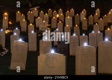 10 novembre 2024. Ricordo la domenica al cimitero militare di Aldershot nell'Hampshire, Inghilterra, Regno Unito. La cerimonia annuale "Lighting of the Graves" ha avuto luogo in serata. Tutte le tombe erano adornate con una candela per ricordare i militari e le donne sepolte qui che furono uccisi nella prima e seconda guerra mondiale e nei successivi conflitti, e tutti quelli uccisi mentre erano in servizio, e un breve atto di memoria fu tenuto in loro onore. Foto Stock