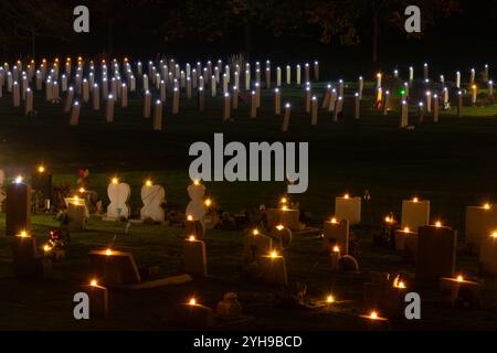 10 novembre 2024. Ricordo la domenica al cimitero militare di Aldershot nell'Hampshire, Inghilterra, Regno Unito. La cerimonia annuale "Lighting of the Graves" ha avuto luogo in serata. Tutte le tombe erano adornate con una candela per ricordare i militari e le donne sepolte qui che furono uccisi nella prima e seconda guerra mondiale e nei successivi conflitti, e tutti quelli uccisi mentre erano in servizio, e un breve atto di memoria fu tenuto in loro onore. Foto Stock