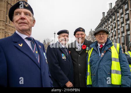 Un gruppo di veterani militari che fingono con un Poppy Cab Marshal. Fondata quindici anni fa dai tassisti di Londra, Poppy Cabs offre viaggi gratuiti per i veterani militari che partecipano all'annuale Remembrance Day Service al Cenotaph di Westminster, Londra. Ispirati al Poppy Appeal della Royal British Legion, dove i distintivi di papavero rosso vengono scambiati con donazioni di beneficenza, questi tassisti si organizzano sotto l'iniziativa "Poppy Cabs". Ogni anno, gli autisti offrono corse gratuite ai veterani dalle principali stazioni ferroviarie di Londra, garantendo loro di arrivare in modo sicuro e puntuale per il loro arrivo Foto Stock