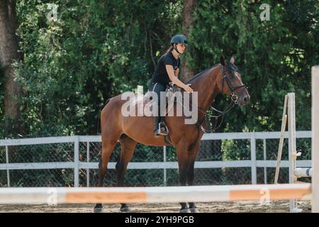 Giovane cavaliere a cavallo che pratica abilità di equitazione in un'arena equestre all'aperto Foto Stock