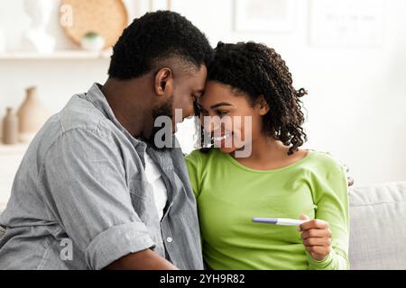 Futuri genitori. Ritratto di coppia nera felice con test di gravidanza positivo Foto Stock