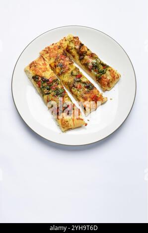 Fette di focaccia cotta in pietra con verdure mediterranee vista dall'alto su piatto bianco isolato su sfondo bianco con spazio di copia Foto Stock