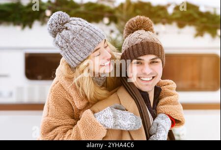 Coppia felice che si gode l'inverno all'aperto, sorridendo in comodi cappelli e cappotti Foto Stock