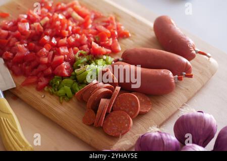 Un assortimento di verdure e salsicce appena tagliate splendidamente disposte su un tagliere di legno Foto Stock
