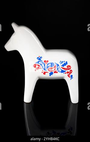 Nova Bana, Slovacchia - 8 novembre 2024 : White Ikea Vinterfest Swedish Dala Horse Ceramic Figurine isolata su sfondo nero. Foto Stock