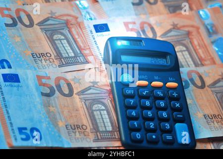 2025 numeri su una calcolatrice e banconote in euro, finanziamenti per l'anno nuovo, illustrazioni monetarie e di bilancio Foto Stock