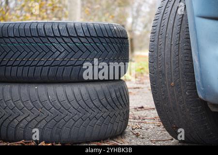 Vista ravvicinata di tre pneumatici per auto che mostrano diversi tipi di battistrada e texture, situati su una strada ricoperta di foglie in un ambiente esterno, illustrando c Foto Stock