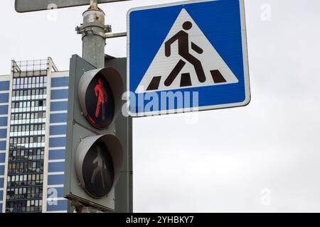 Un segnale di attraversamento pedonale è posizionato comodamente accanto a un semaforo per una migliore visibilità e sicurezza per coloro che attraversano la strada Foto Stock