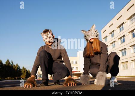 Ragazza e ragazzo quadrober in maschera gatto siedono in città, bambini quadroberi, sottocultura Foto Stock