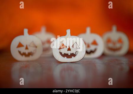 Zucche in legno in miniatura con facce tagliate con sfondo arancione, Halloween Foto Stock