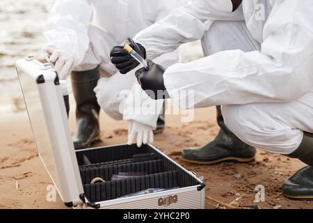 Primo piano di due scienziati che aprono il kit di test mentre si eseguono sonde all'aperto con acqua e trattengono provette, copiare spazio Foto Stock