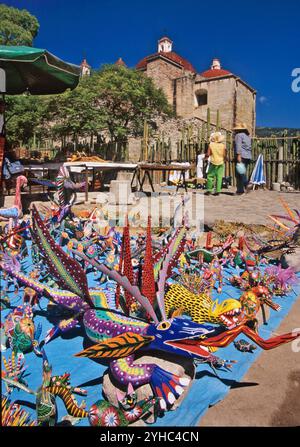 Sculture in legno in mostra, banchina del mercato vicino al Grupo de la Iglesia (complesso della Chiesa), Mitla, vicino a Oaxaca, Stato di Oaxaca, Messico Foto Stock