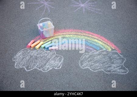 Disegno del gesso del marciapiede. Un arcobaleno e nuvole cielo dipinto sull'asfalto. Attività per bambini. Sfondo colorato con gesso. Parco giochi all'aperto per la scuola Foto Stock