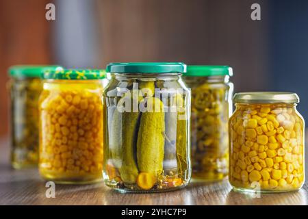 Verdure in scatola. Mais sottaceto, cetrioli e peperoni jalapeno su un tavolo di legno. Foto Stock