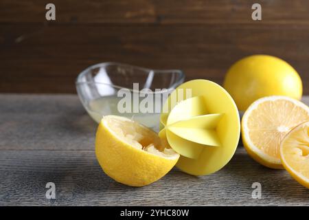 Centrifuga in plastica e limoni freschi su tavolo in legno grigio, primo piano Foto Stock