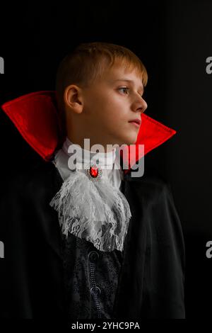 Ritratto di un ragazzo che indossa un costume da vampiro in posa su uno sfondo nero. Foto Stock