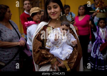 Un adolescente vestito da Vergine del Carmelo tiene un Gesù bambino durante il quartiere Calenda di Carmen Bajo a Oaxaca, in Messico. Foto Stock