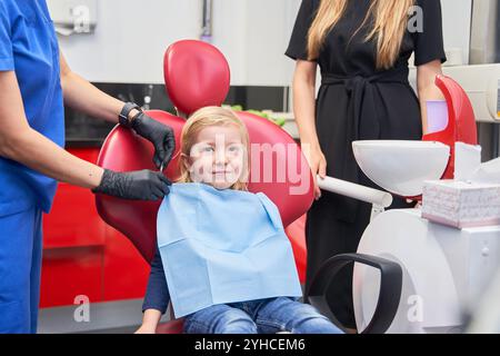 Una madre e Una figlia da Un dentista. Una bambina carina seduta sulla sedia di un dentista con sua madre, che fa un esame dentistico Foto Stock