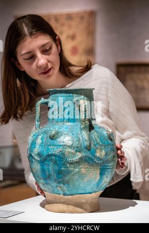 Londra, Regno Unito. 11 novembre 2024. Un membro del personale con «Un grande vaso di ceramica monocromatica Kashan», Persia, XII secolo, (circa £ 800 - £ 1.200), in anteprima della vendita di arte islamica e indiana di Bonham. Le opere saranno messe in vendita presso le gallerie Bonhams New Bond Street il 12 novembre. Crediti: Stephen Chung / Alamy Live News Foto Stock