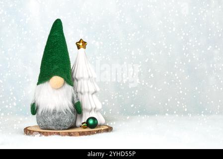 Gnomo natalizio con un albero di natale su una base di legno e fiocchi di neve con spazio per testo sulla neve. Sfondo del concept natalizio Foto Stock