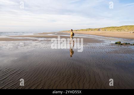 Figura umana sulla spiaggia del Mare del Nord con le dune di sabbia sullo sfondo non lontano dalla città di Den Helder, nella provincia dell'Olanda settentrionale, i Paesi Bassi Foto Stock